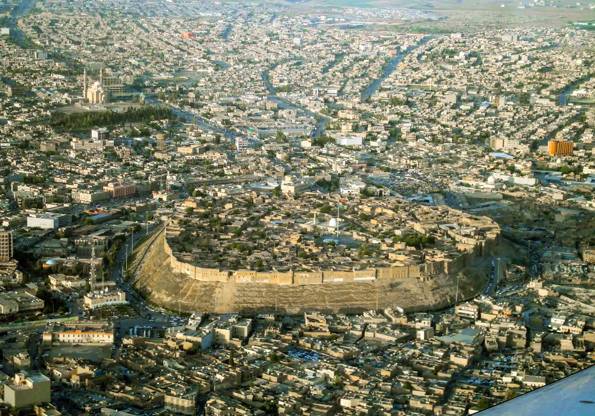 The Citadel of Erbil from the air — the walled oval of the old city on its tell, with the streets of modern Erbil radiating out around it.