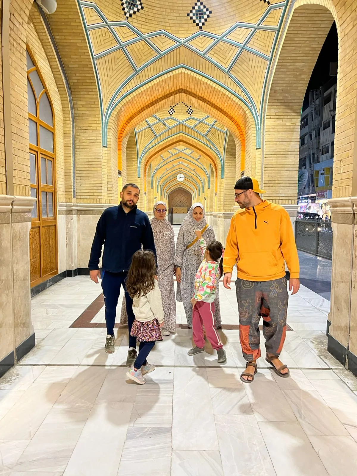 Visitors walking out through a tiled gateway, the vault above them worked in blue and gold.