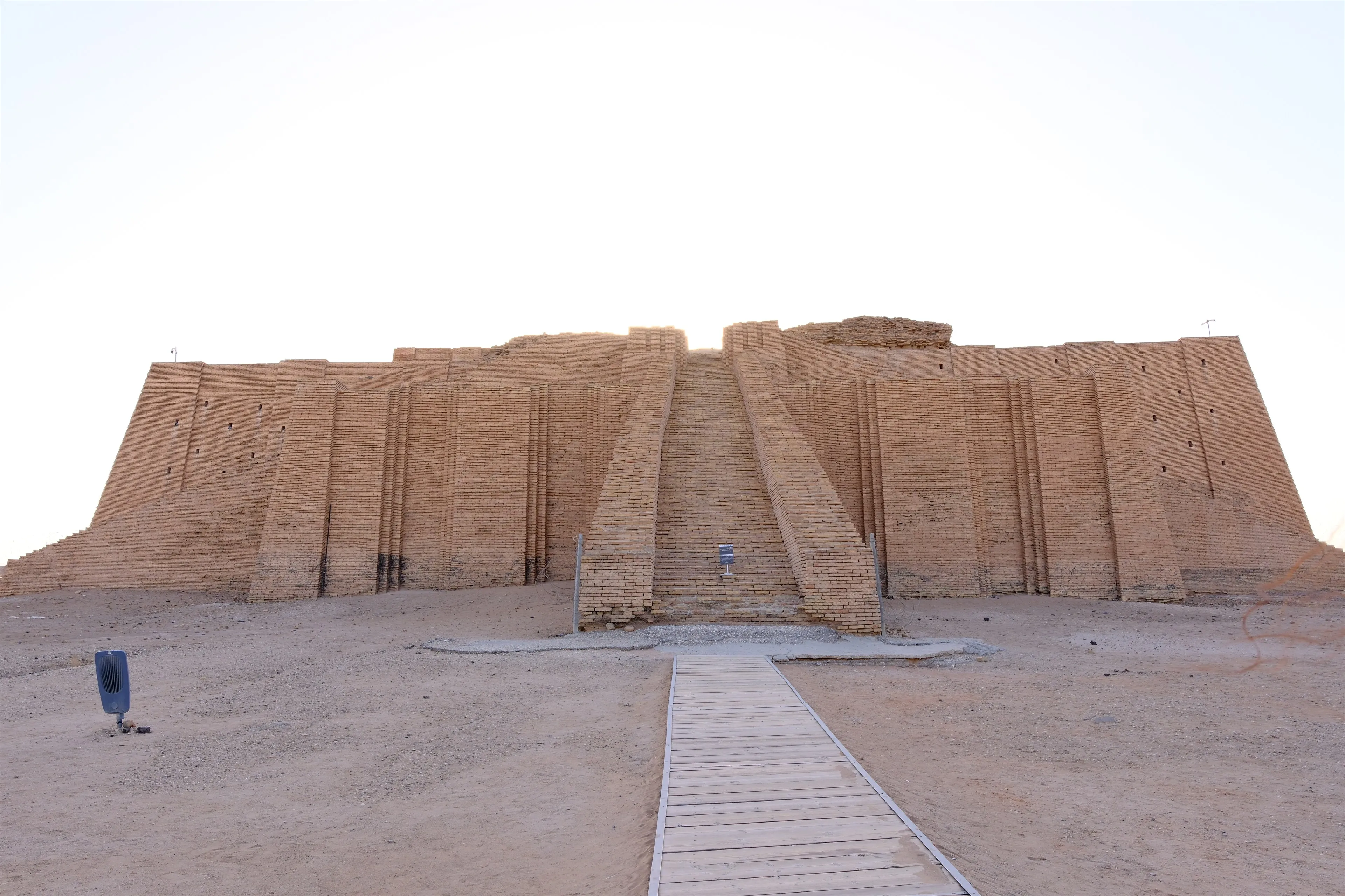 The Great Ziggurat of Ur seen head-on, its triple ceremonial staircase climbing the buttressed mudbrick terraces from the desert floor.